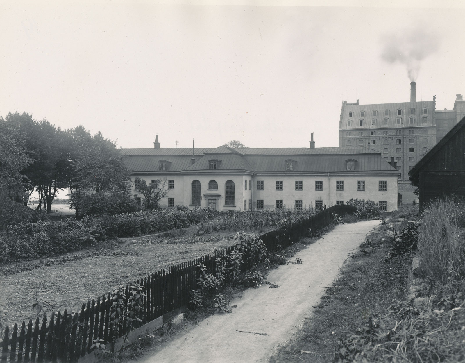Huvudbyggnaden, med kyrkan och sjuksalarna, som ännu står kvar. Fotograf Aktiebolaget Saltsjöqvarn 1915. Nacka lokalhistoriska arkiv.