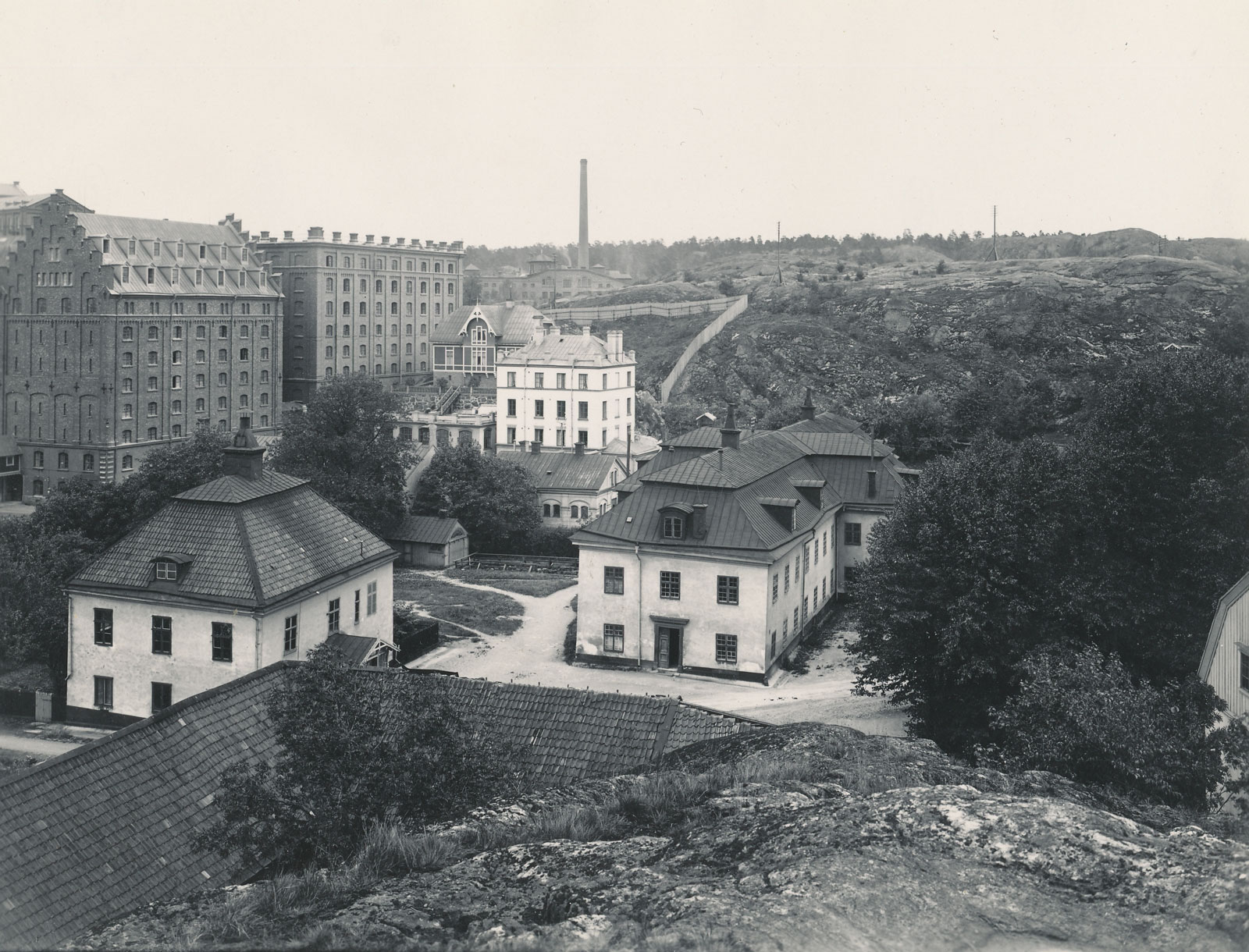 Längs till vänster Saltsjöqvarns byggnader och hospitalsbyggnaderna syns närmast kameran. Den stora byggnaden i mitten står ännu kvar. Snett till vänster syns ett kombinerat kontor och bostad för hospitalets ledning. Foto Saltsjöqvarn 1915. Nacka Lokalhistoriska arkiv.