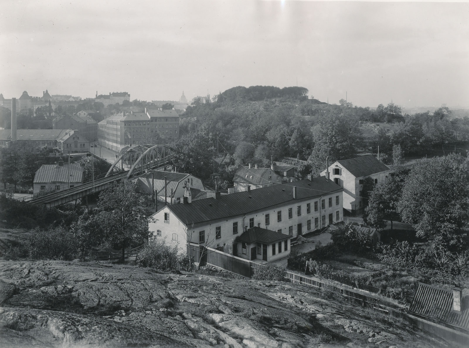 Hospitalets ekonomibyggnad och bron med Saltsjöbanan. Uppe till vänster syns den nu försvunna Danviksgatan från Söder och Liljeholmens fabriker. Foto Aktiebolaget Saltsjöqvarn 1915. Nacka Lokalhistoriska arkiv.