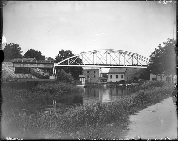 Sedan början av 1890-talet strök Saltsjöbanan förbi Hospitalets entré vid Hammarby sjös utlopp. Här är den första bron som senare ersattes av en klaffbro då kanalen grävdes ut. Fotografen står på landsvägen ut mot Värmdö, nedanför Danviksklippan där kanalen idag går. Foto Carl Johan Gimberg 1896. Stockholms stadsmuseum Fotonummer Fa 3838.