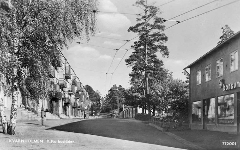 Smalhuset till vänster och Konsum till höger på 1940-talet. Radhusen skymtar framme till höger. Lägg märke till trådarna till bussen och lastbilarna. Adressen var först Stora Gatan. När bron byggts blev namnet Tre Kronors väg. Vykort. Kooperativa Förbundet.