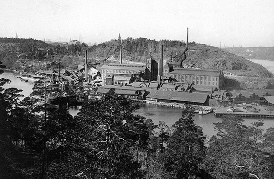 Superfostfatfabriken i Svindersviken från bergen i söder på 1930-talet. Observera skorstenen, uppe till höger, för giftiga gaser på Finnberget, som då hette Skatberget. Det sades att det var dött omkring den. Fotograf okänd. Nacka lokalhistoriska arkiv.